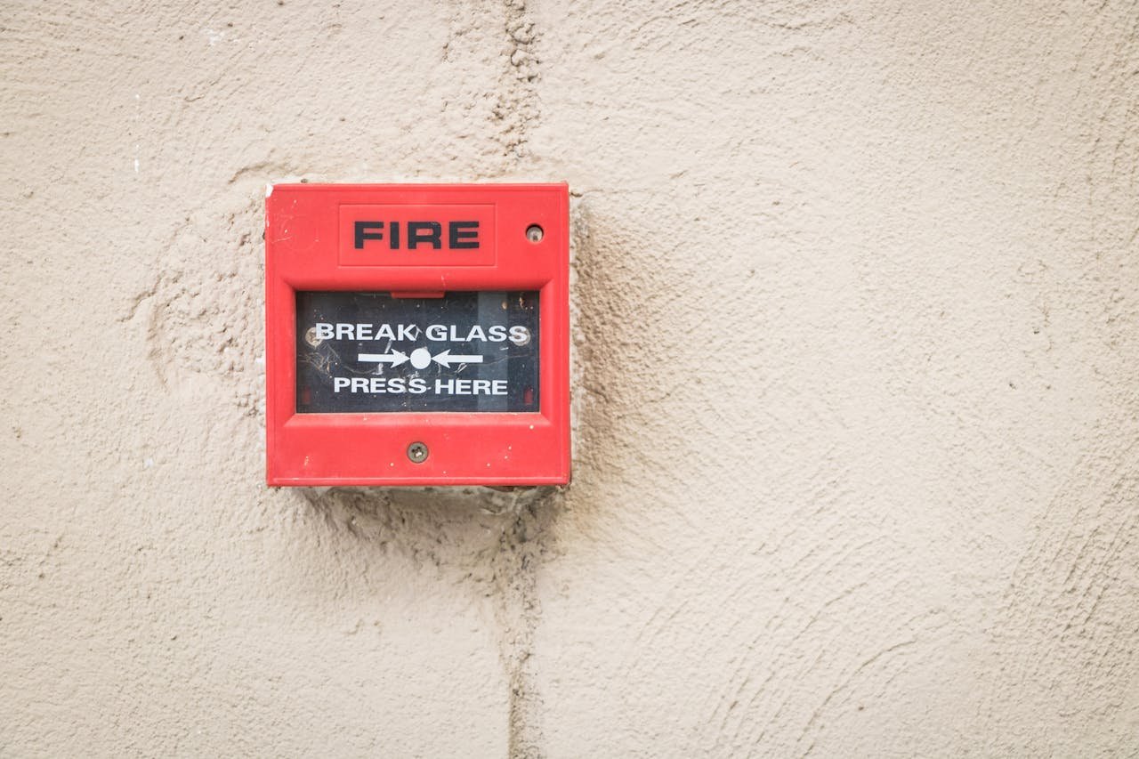 Services Close-up of a red fire alarm mounted on a textured wall, ready for emergency use.
